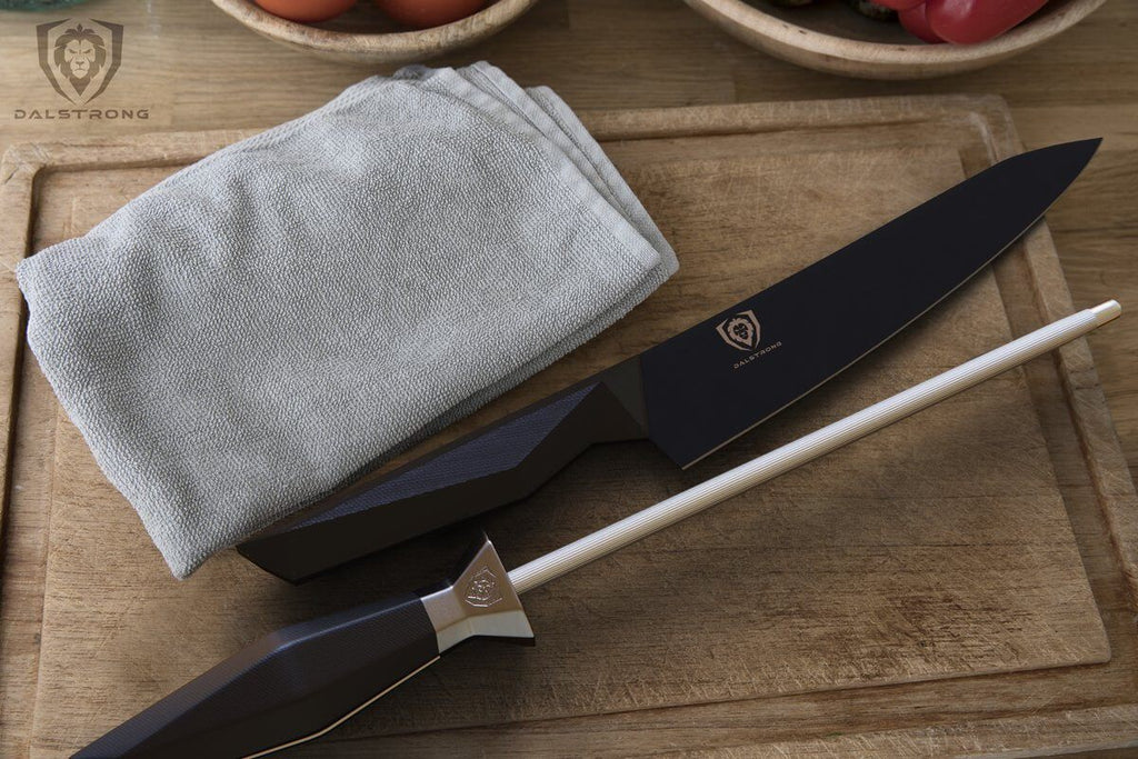 A grey towel on a brown cutting board next to a black chef knife and silver honing steel