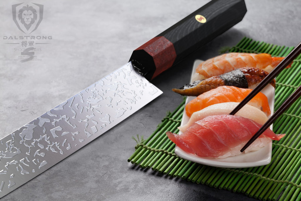 Chopsticks lifting a piece of orange sushi from a plate next to a sushi knife