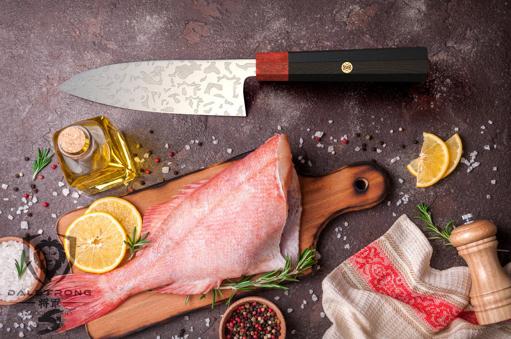 Deba knife beside a chopped raw fish on a cutting board surrounded by cooking ingredients such as salt and lemon