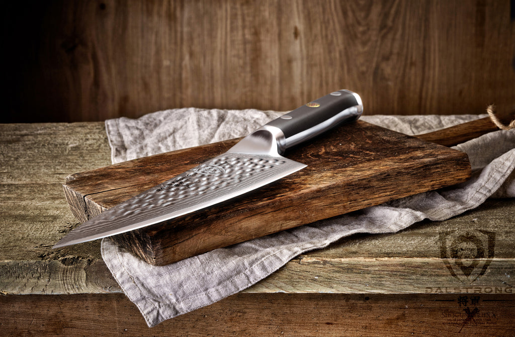 A sharp gyuto knife with damascus steel on a wooden cutting board