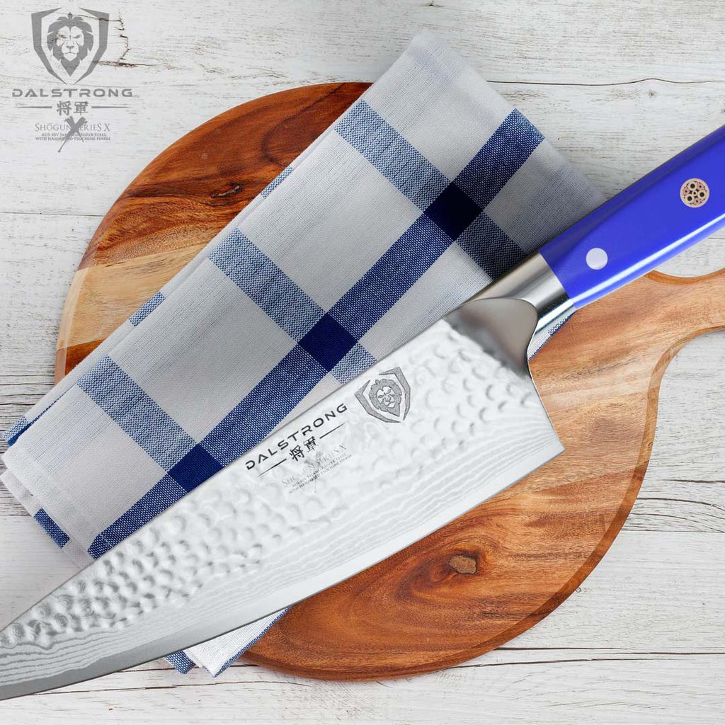 A photo of the Chef's Knife 8" Blue Handle | Shogun Series X | Dalstrong on top of a round wooden board.