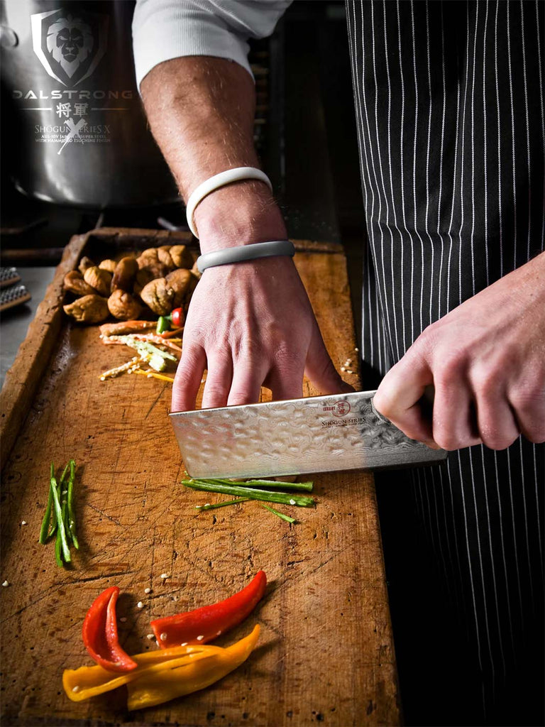 A man using the Nakiri Vegetable Knife 6" Shogun Series ELITE with sliced bell peppers.