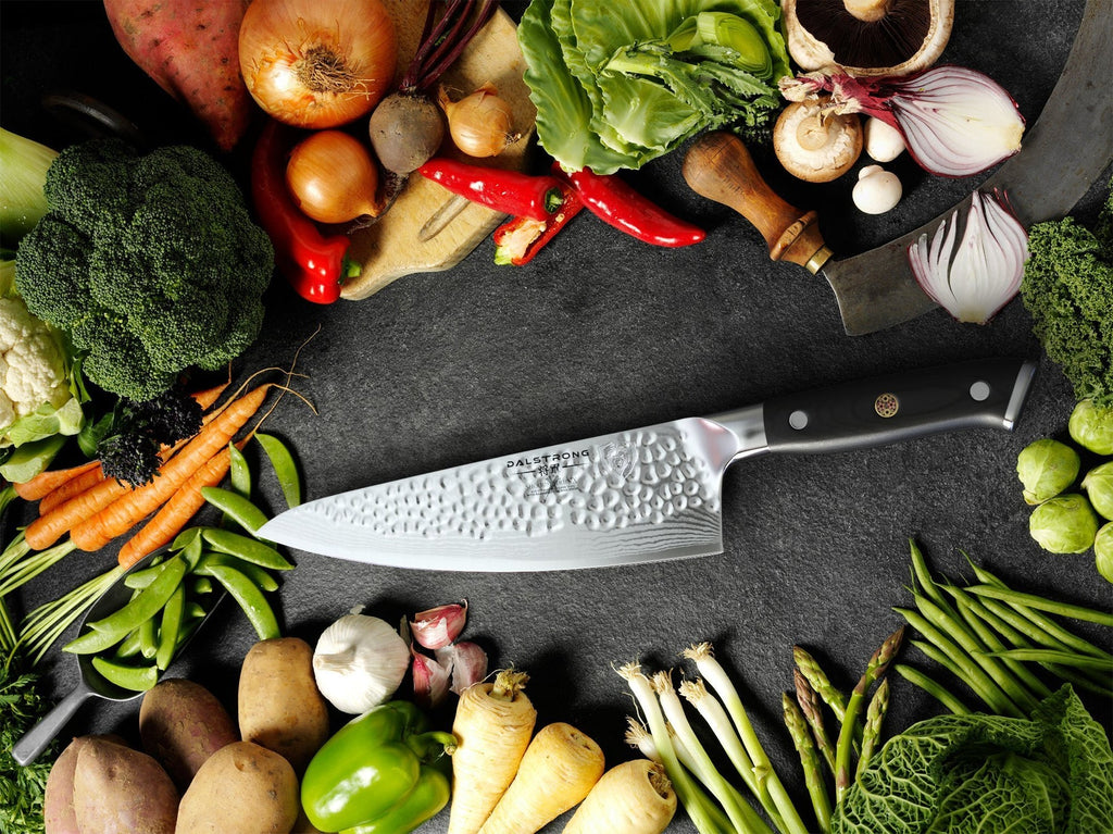 Dalstrong Shogun Series X Chefs Knife on a black table with a wide array of vegetables around.