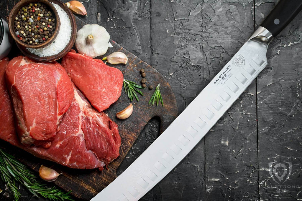 Long silver butcher knife next to uncooked meats and salts 