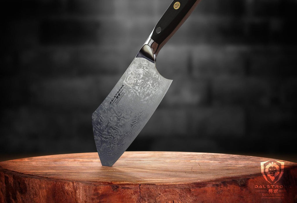 Mini cleaver with damascus steel sticking into a cutting board by the tip of the blade