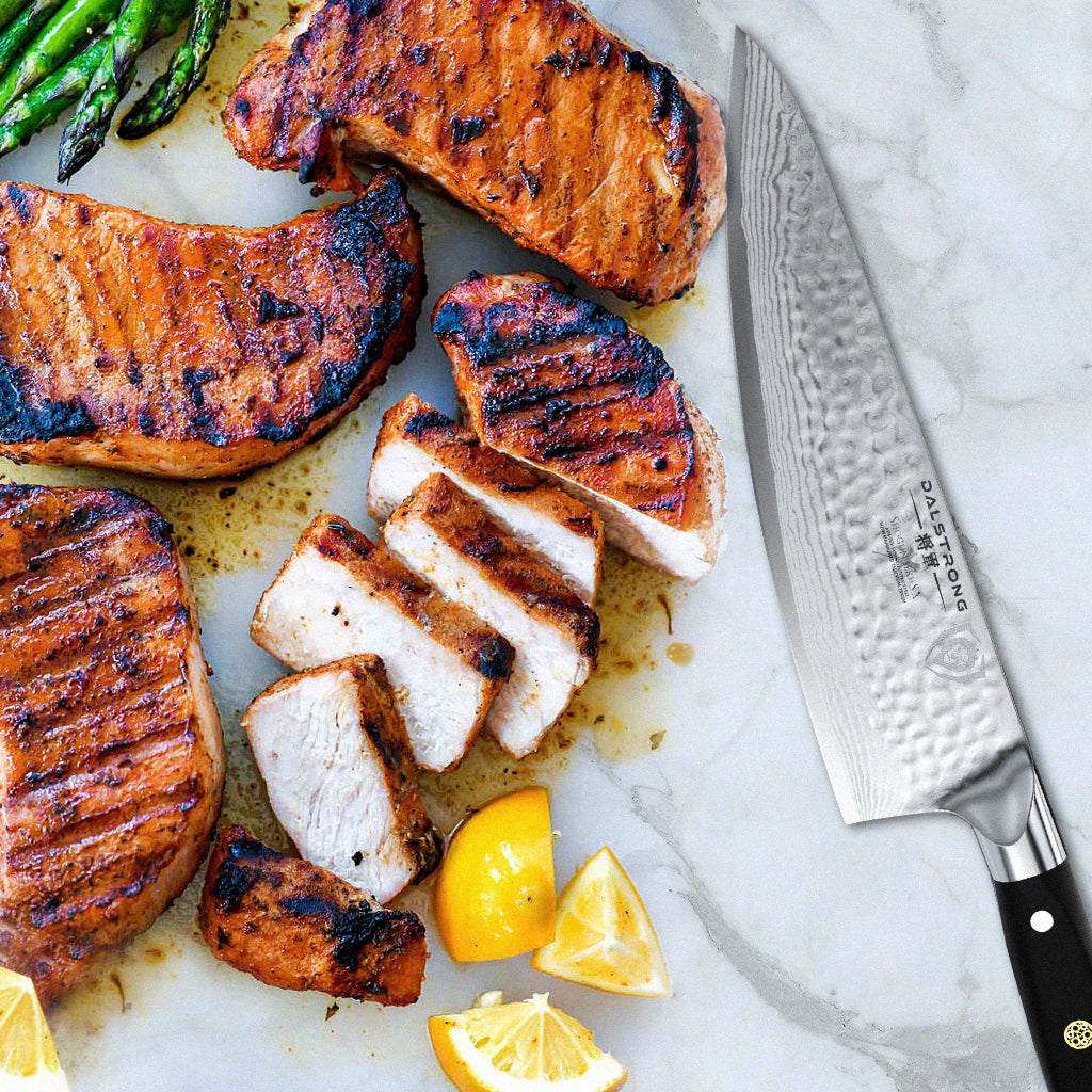 Sliced pork chops next to chopped lemon wedges and a sharp kitchen knife