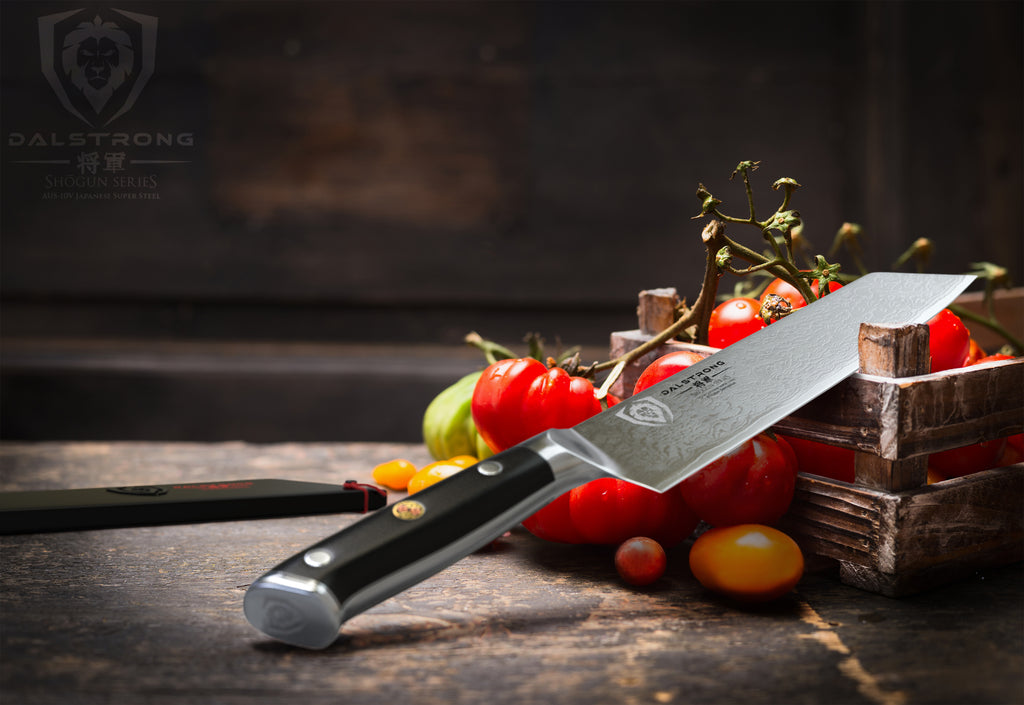 A kiritsuke knife with a black handle leaning on a crate of produce 