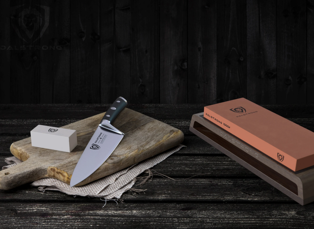 Dalstrong Premium Whetstone Kit on a wooden table next to a cutting board with a chef knife on it