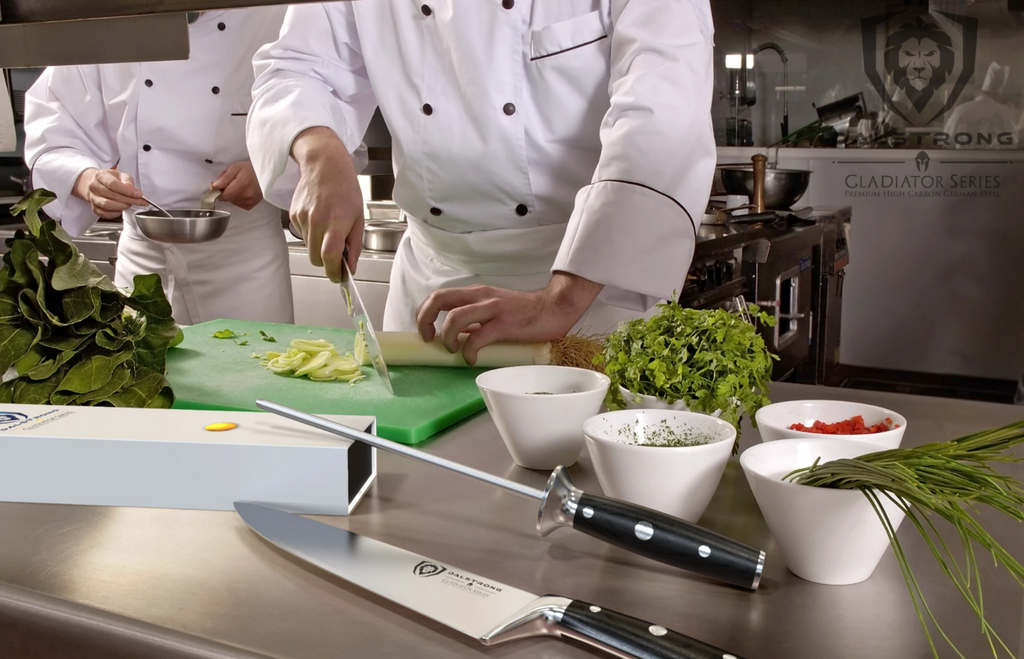 A busy chef kitchen with a knife and honing steel in the foreground