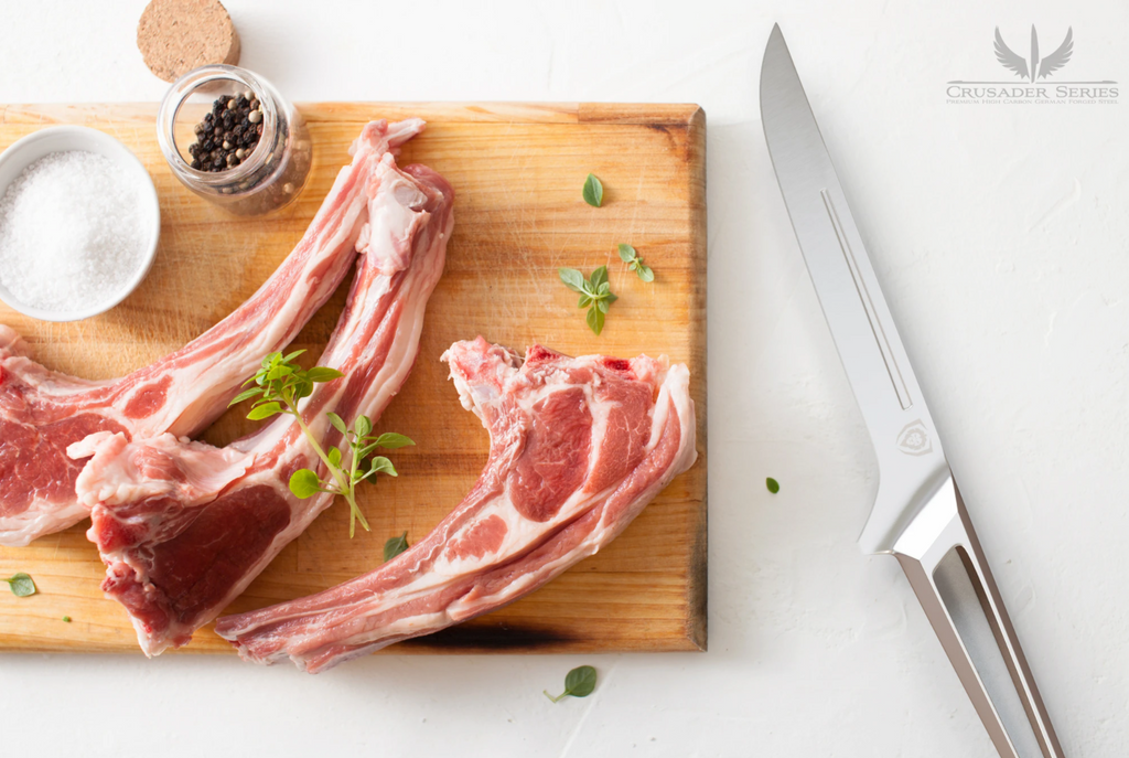 Uncooked meat on a brown cutting board next to a stainless steel boning knife on a white surface