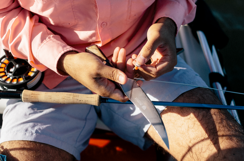 Close up of man in shorts holding a sharp fillet knife