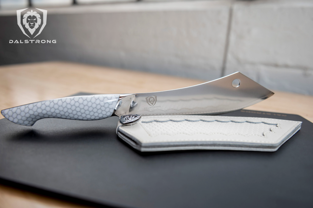 A cleaver chef knife hybrid balancing on a black cutting board next to its protective sheath