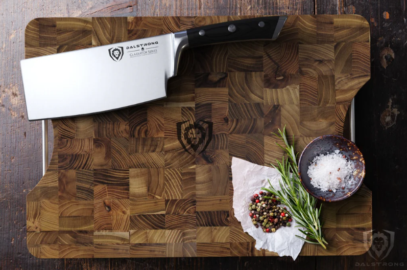 A photo of the Lionswood Teak Cutting Board Medium Size Dalstrong with spices and a Dalstrong cleaver on top of it.