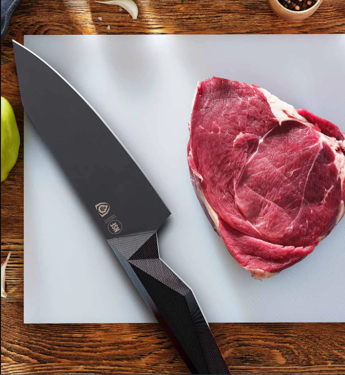 A photo of a huge piece of steak with the Chef's Knife 6" Shadow Black Series NSF Certified Dalstrong on top of a white board