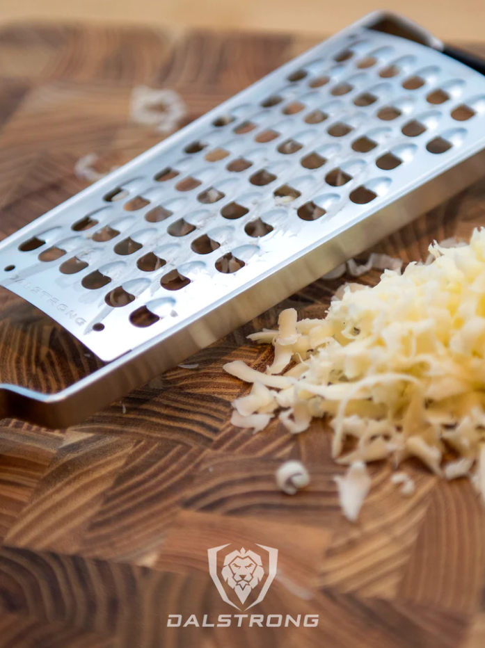 Professional Extra Coarse Wide Grater with grated cheese on top of the Dalstrong wooden borad