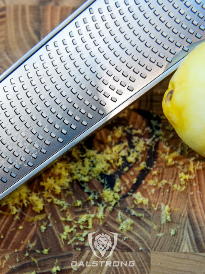 Professional Zester Narrow Grater with grated lemon zest on top of the Dalstrong wooden board