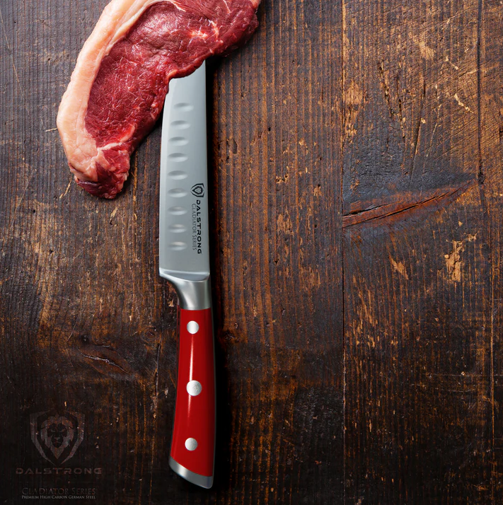 A photo of the 4-Piece Straight-Edge Steak Knife Set Red ABS Handles Gladiator Series NSF Certified Dalstrong and a piece of steak on top of a wooden table