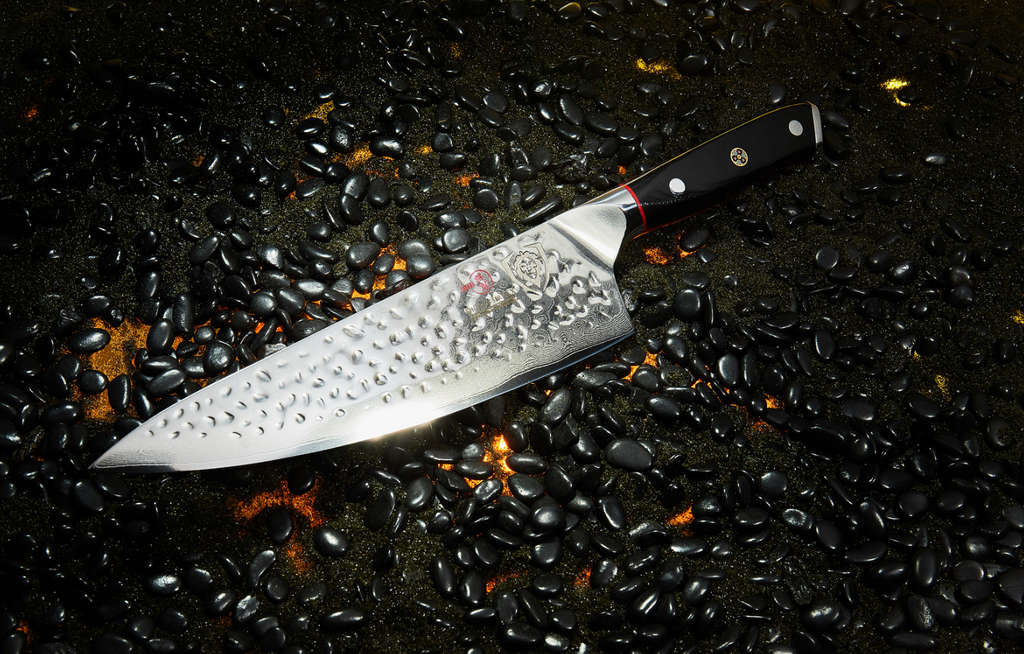 A close-up photo of the Chef's Knife 8" Shogun Series ELITE Dalstrong on a burning black surface with black pebbles