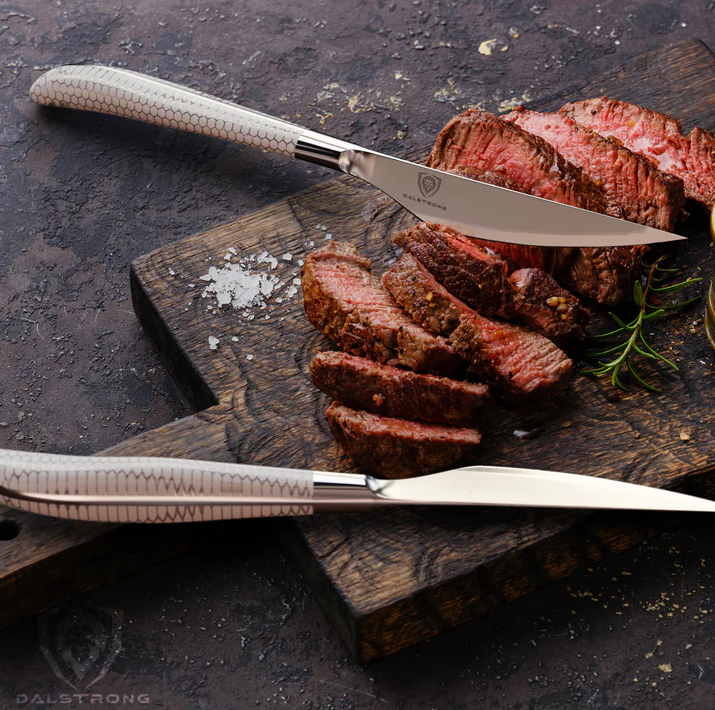 A photo of a beautiful slices of steak with the 4-Piece Steak Knife Set Frost Fire Series NSF Certified Dalstrong on top of a wooden board