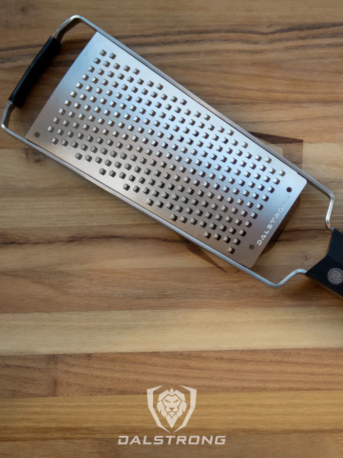 A photo of the Dalstrong Professional Coarse Wide Cheese Grater on top of the Dalstrong wooden board.