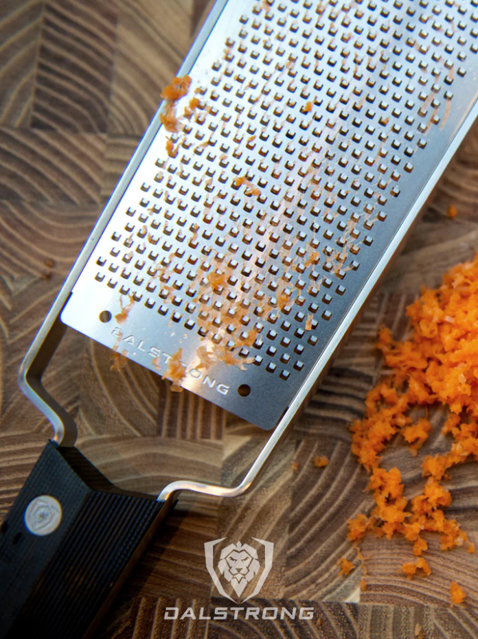 Professional Fine Wide Grater Dalstrong with grated carrots on a wooden cutting board
