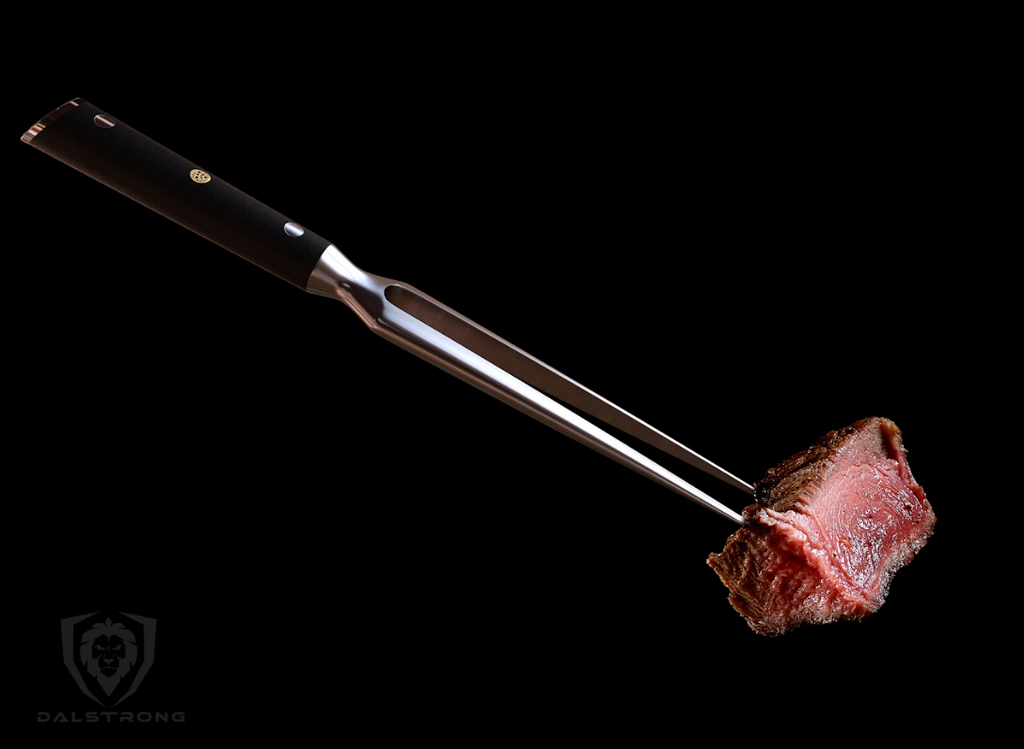The photo of the Meat & Carving Fork 7" The Impaler | Dalstrong with a piece of meat on the tip.