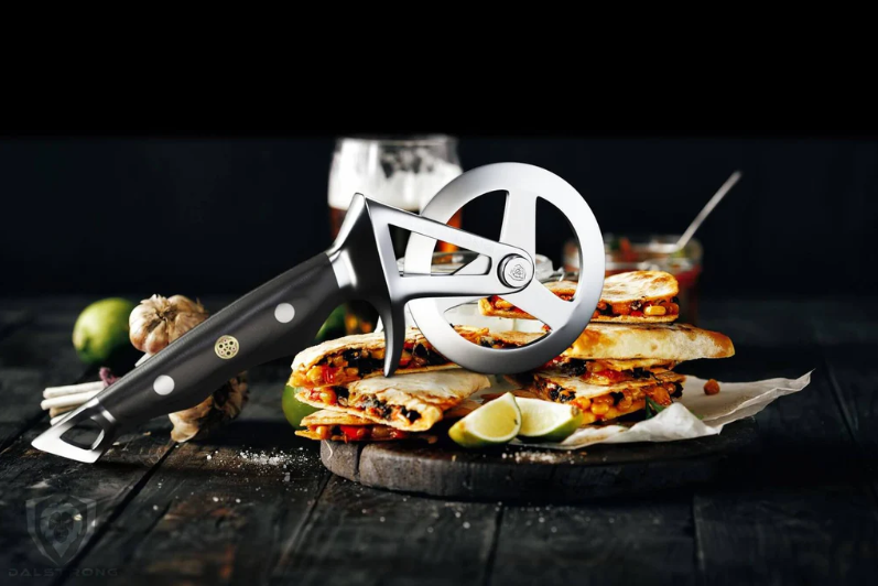 A photo of the Dalstrong Orbit Razor Pizza Wheel & Cutter with perfectly sliced quesadillas on top of a wooden board.