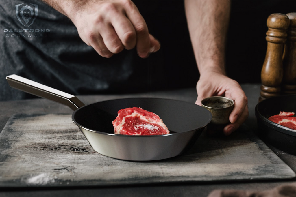 A photo of a mans hand seasoning the steak inside the 10" Frying Pan & Skillet ETERNA Non-Stick Oberon Series Dalstrong