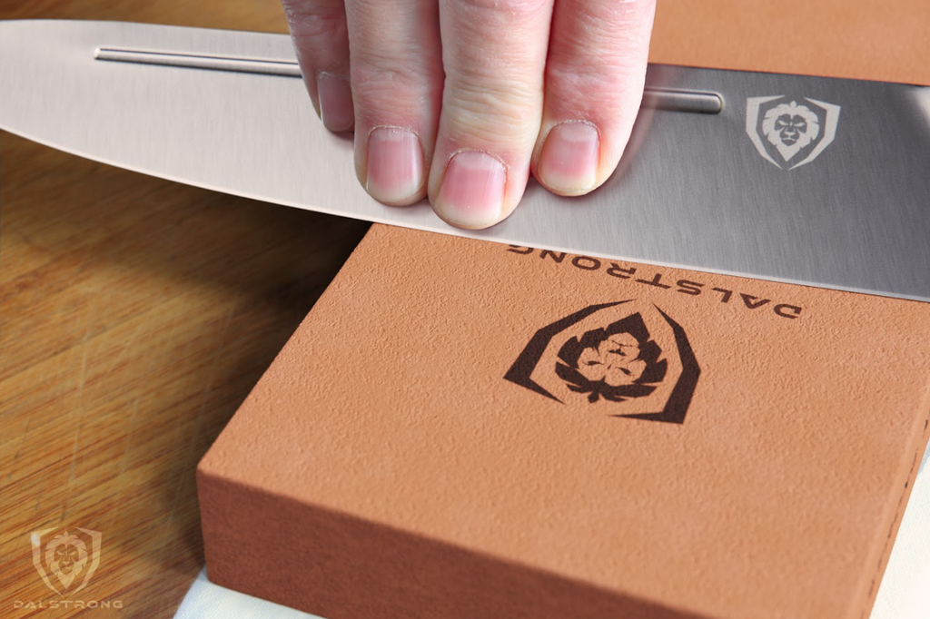 A close-up photo of a hand sharpening a Dalstrong knife using the #400 / #1000 Grit Premium Whetstone Set Dalstrong