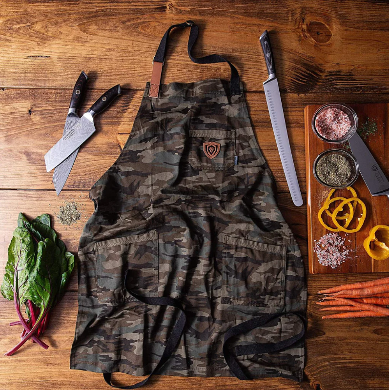 Camouflage styled kitchen apron next to kitchen knives on a wooden surface 