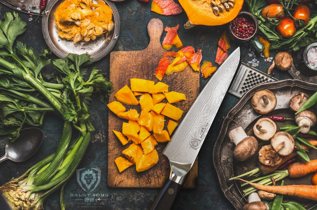 A photo of diced squash with Chef's Knife 7" Shogun Series ELITE Dalstrong beside it on top of a wooden board.