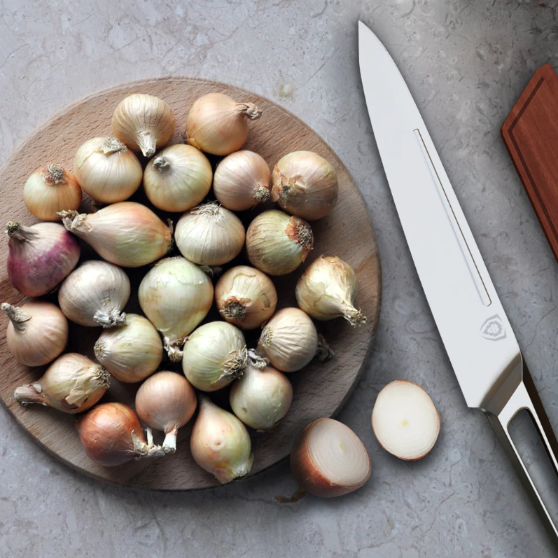 A plate of whole shallot onions next to a stainless steel kitchen knife