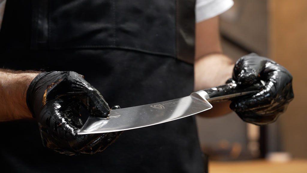 A man with black apron and gloves holding the Gladiator Series Chef's Knife & Cleaver Hybrid 8"