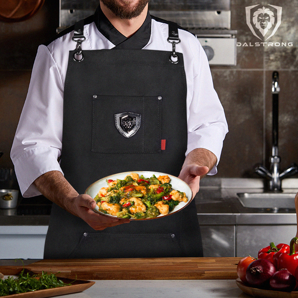 Chef wearing Dalstrong Professional Chef's Kitchen Apron - Sous Team 6" and holding a plate of stir fry