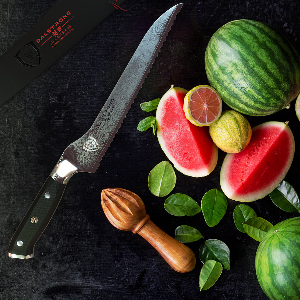 An offset bread knife next to a pile of sliced and unsliced watermelons 