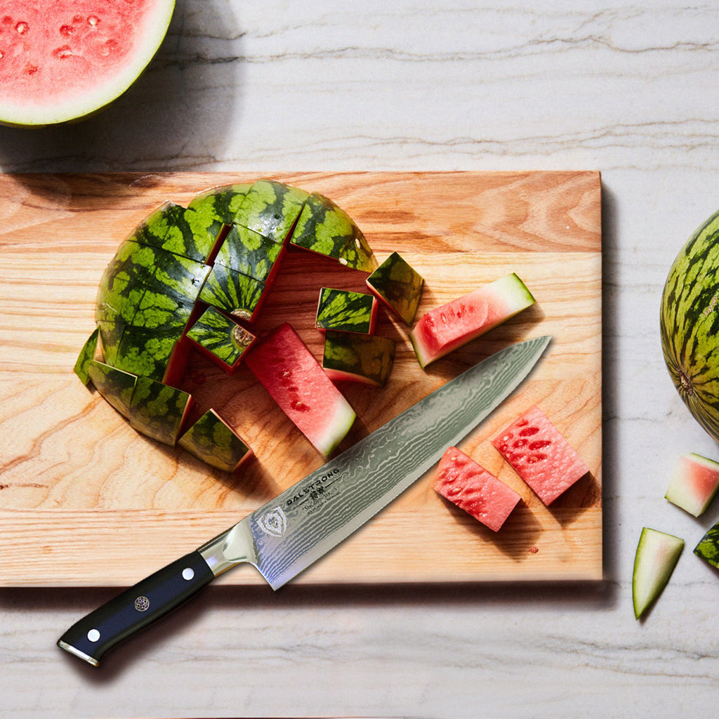 A partly chopped watermelon on a wooden cutting board next to a sharp kitchen knife
