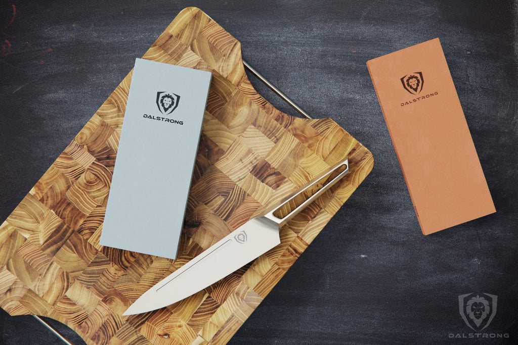 Stainless Steel Knife and a grey whetstone rest on a large wooden cutting board with a second whetstone on the table next to the board