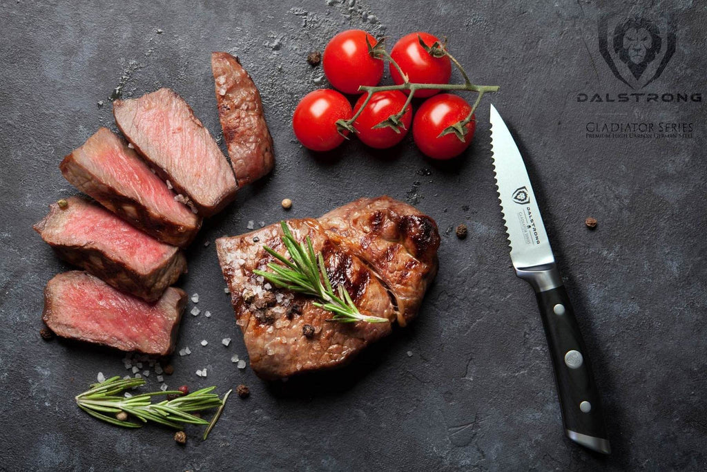A serrated paring knife next to several slices of medium rare steak and cherry tomatoes 