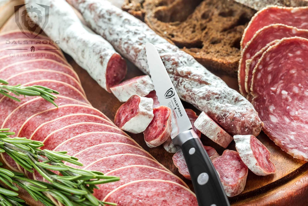 A tray of deli meat and garnish with a sharp utility knife next to it