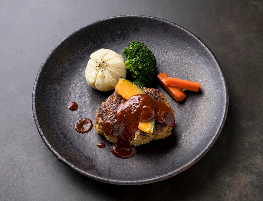 Gourmet patty with vegetables on the side and thick gravy being added on top