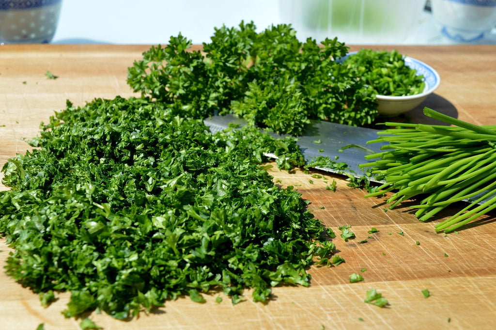 Fresh parsley chopped on a wooden cutting board using a chef knife