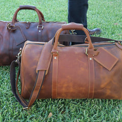 Two brown leather bags placed on grass