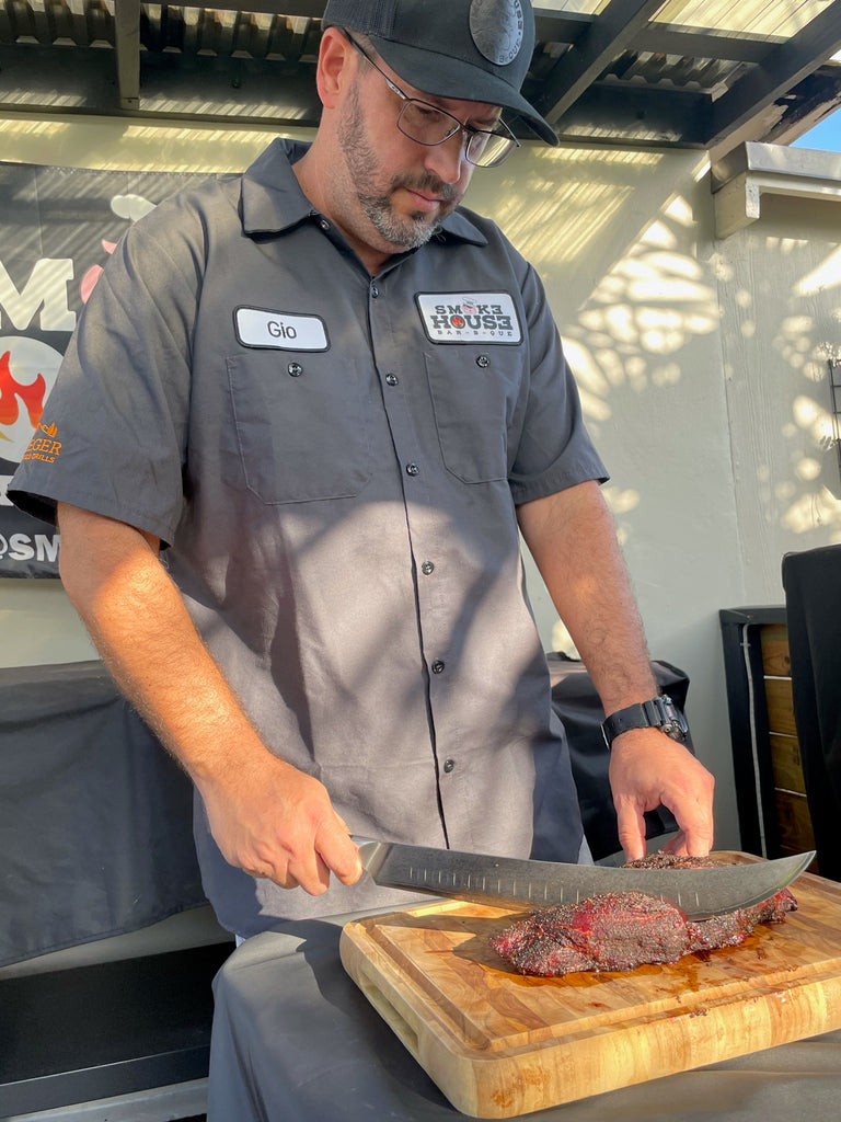 Giovanni Borges (Smok3hous3_bbq) slicing through meat with the Shogun Series 10" Butcher's Breaking Cimitar Knife