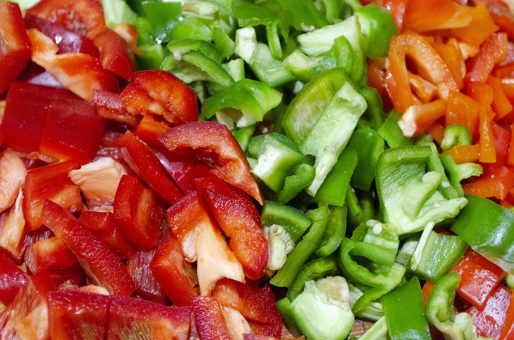 A photo of fresh and raw slices of red and green bell peppers.