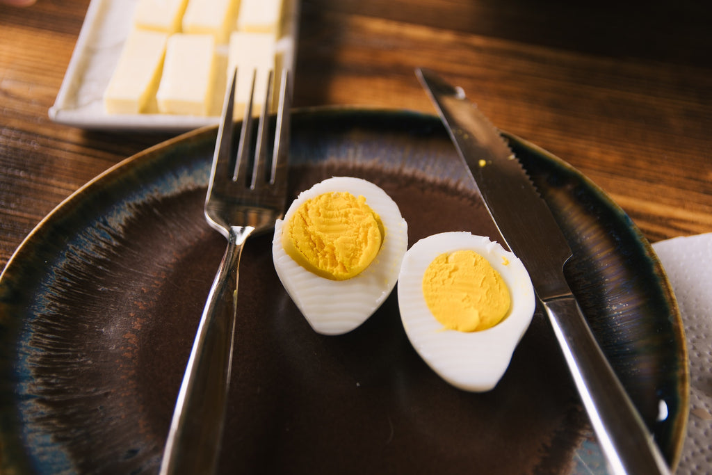 A photo of a sliced egg on black plate