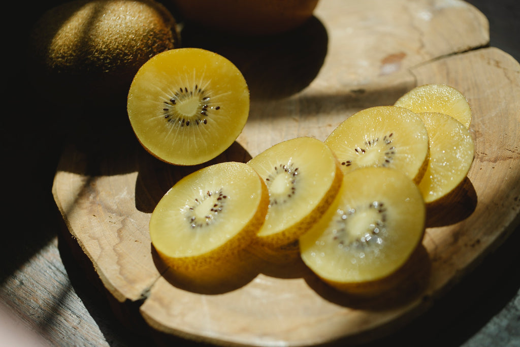 Seven slices of fresh kiwi on top of a wooden board at sunshine