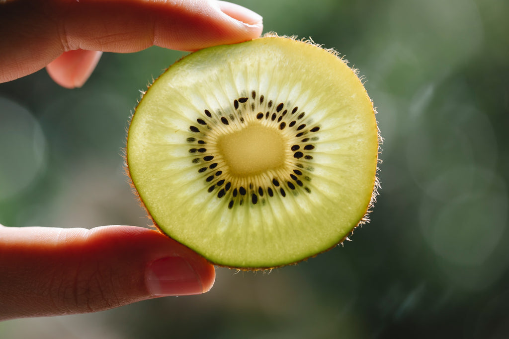 Close-up photo of a person showing a perfect slice of fesh kiwi