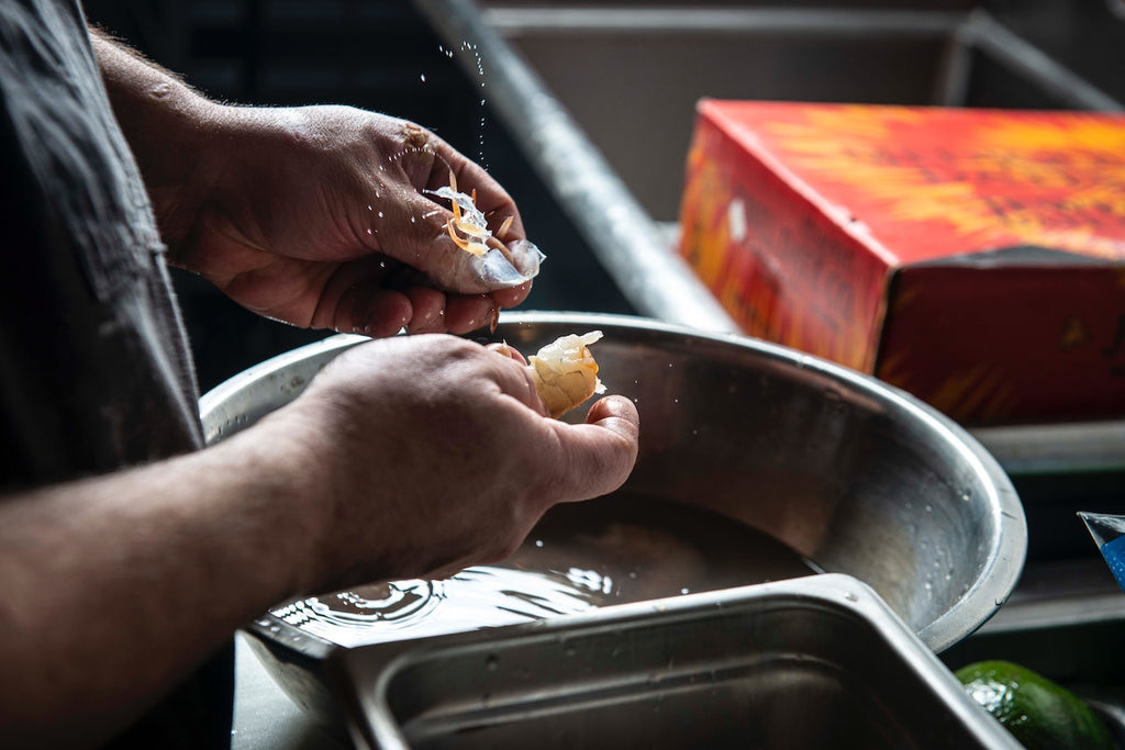 A close-up shot of a man peeling a shrimp.