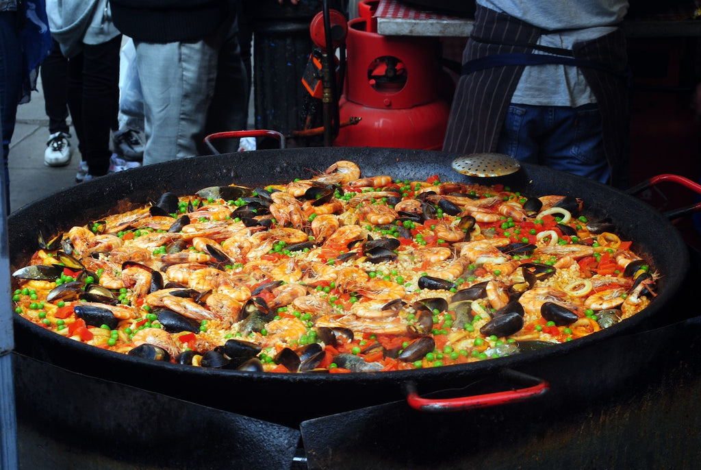 A big wok of freshly cooked Paella with lots of mollusks being cooked and sold in the streets.