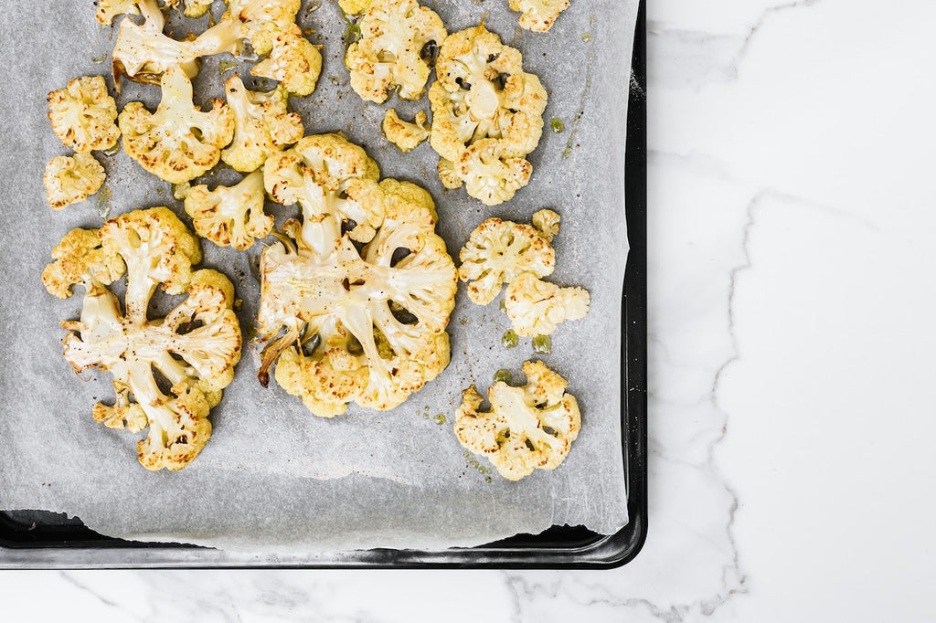 Overhead shot of cauliflower cuts on a tray freshly baked from the oven.